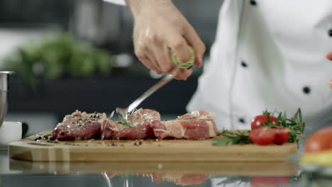 close up view of chef cooking raw steak in restaurant kitchen