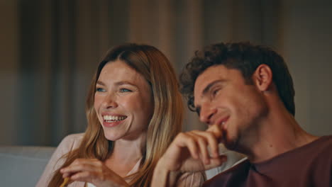 talking friends eating snacks at home cinema closeup. laughing pair enjoying tv