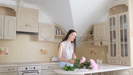 a woman makes a bouquet of pink peonies creating home comfort a young girl collects a bouquet of flowers creates home comfort