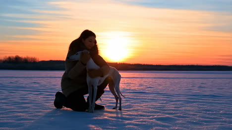 woman hugging her dog at sunset in winter