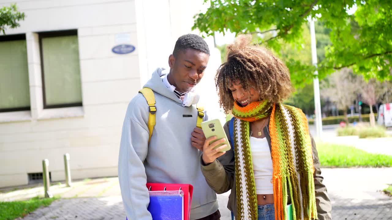 Two students looking at a smartphone on campus
