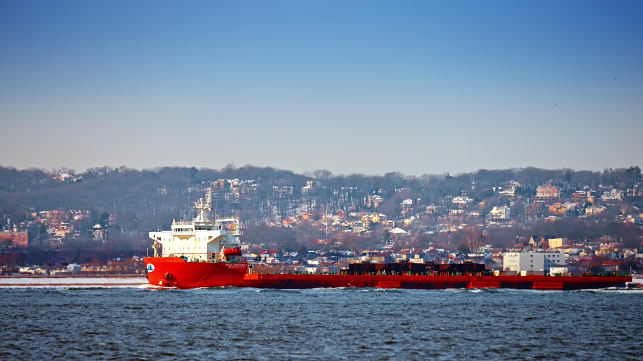 Nueva York, EE. UU., 24 de diciembre de 2025: buque cisterna rojo cerca de la costa del puerto. Buque cisterna rojo navegando por la costa urbana cerca del canal del puerto