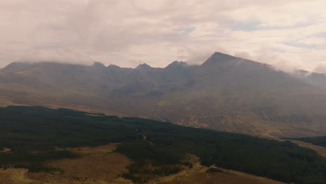 aerial drone view of dramatic mountain scenery in the scottish highlands, with rugged peaks, rolling mist, and atmospheric light creating a breathtaking cinematic landscape