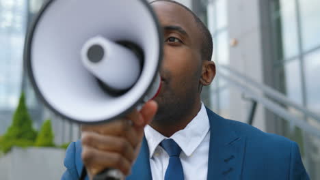 vista de cerca de un joven afroamericano elegante hablando por un altavoz en la calle