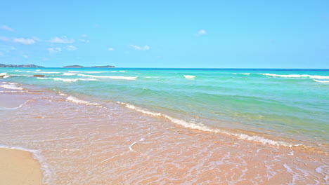 Waves-from-turquoise-ocean-waters-wash-up-on-a-golden-sandy-beach