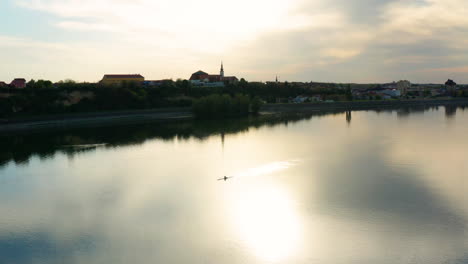 man rowing boat in danube river near vukovar city during sunset in croatia