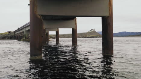 view under rusty storseisundet bridge at atlantic ocean road with moving water