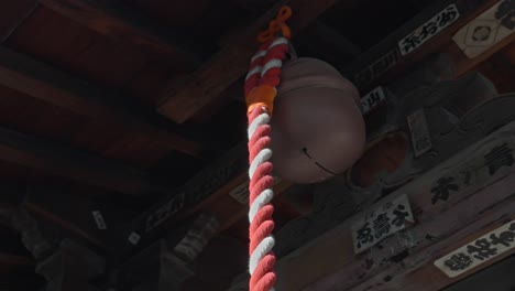 a large temple bell hangs from a wooden structure, its rope ready to be pulled, echoing ancient traditions and spiritual practices.