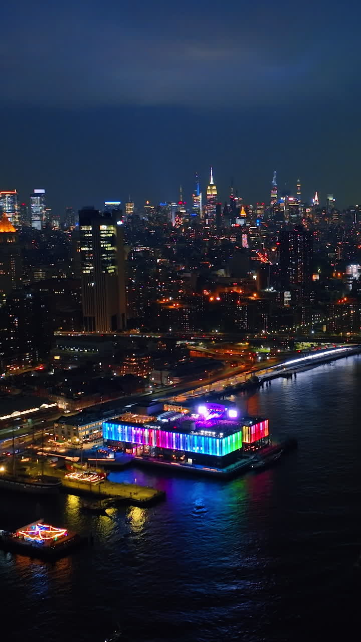 Vibrant New York at night time. Drone footage of stunning cityscape from above the river. Vertical video