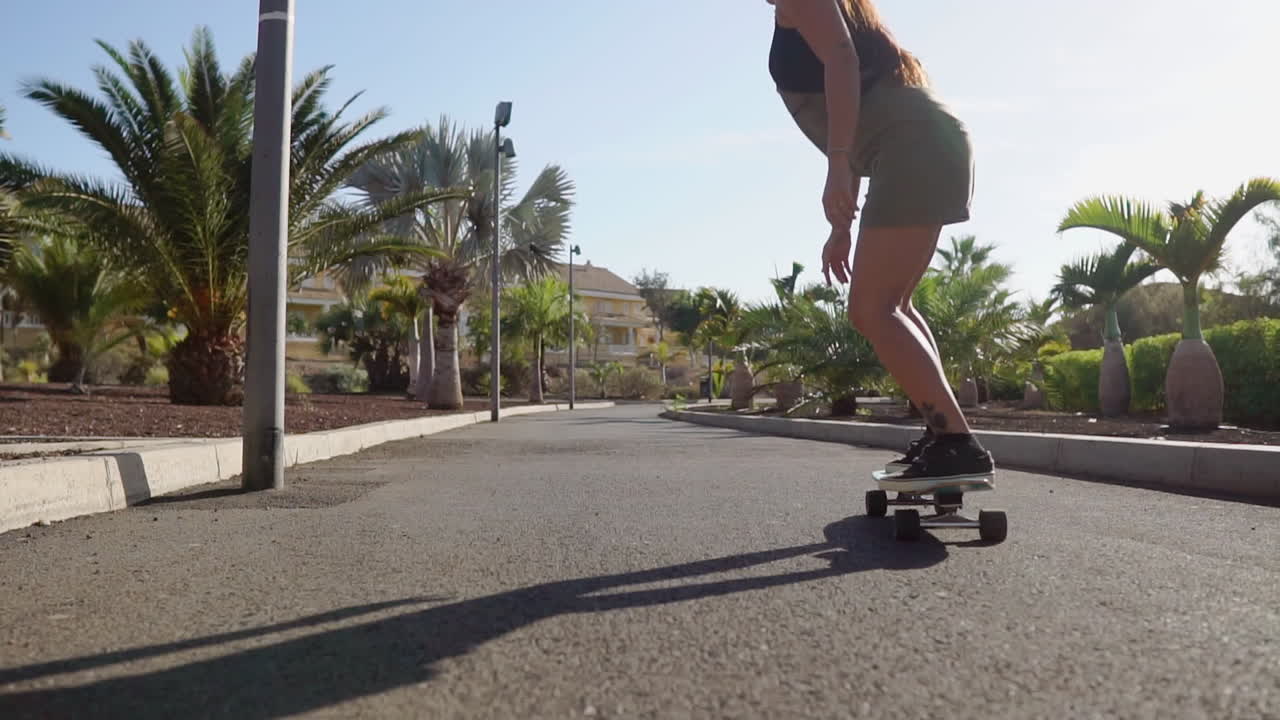 Captured in slow motion, a young girl's longboard journey by the beach and palm trees exudes elegance and beauty