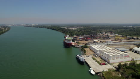 aerial view of a tanker unloading oil into silos at a shipyard near a river