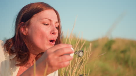close up woman blowing delicate soap bubbles that drift then burst in golden sunset light over grassy hill, rainbow sheen shimmering before popping gently against blurred