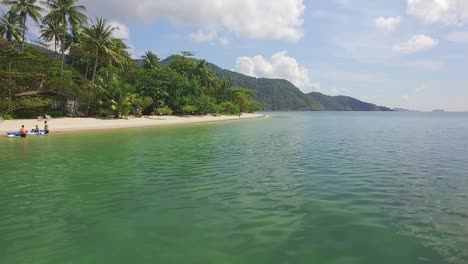 Aerial-forward-dolly-low-angle-of-a-beach-with-palm-trees-on-Koh-Chang-with-Jungle,-sea-view-and-resort