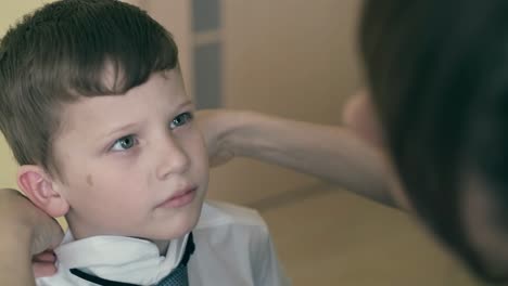 madre viste a un niño a la escuela endereza su ropa 4