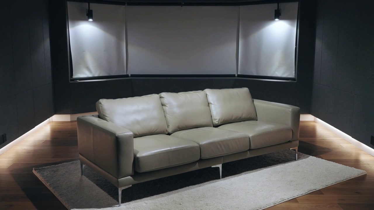 La telecamera riprende un divano in pelle a tre posti centrato nello showroom, che mette in mostra l'illuminazione a LED della base