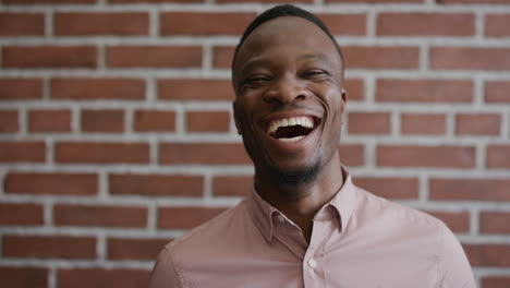 portrait professional young african american businessman laughing enjoying successful lifestyle confident black male entrepreneur on brick wall background slow motion