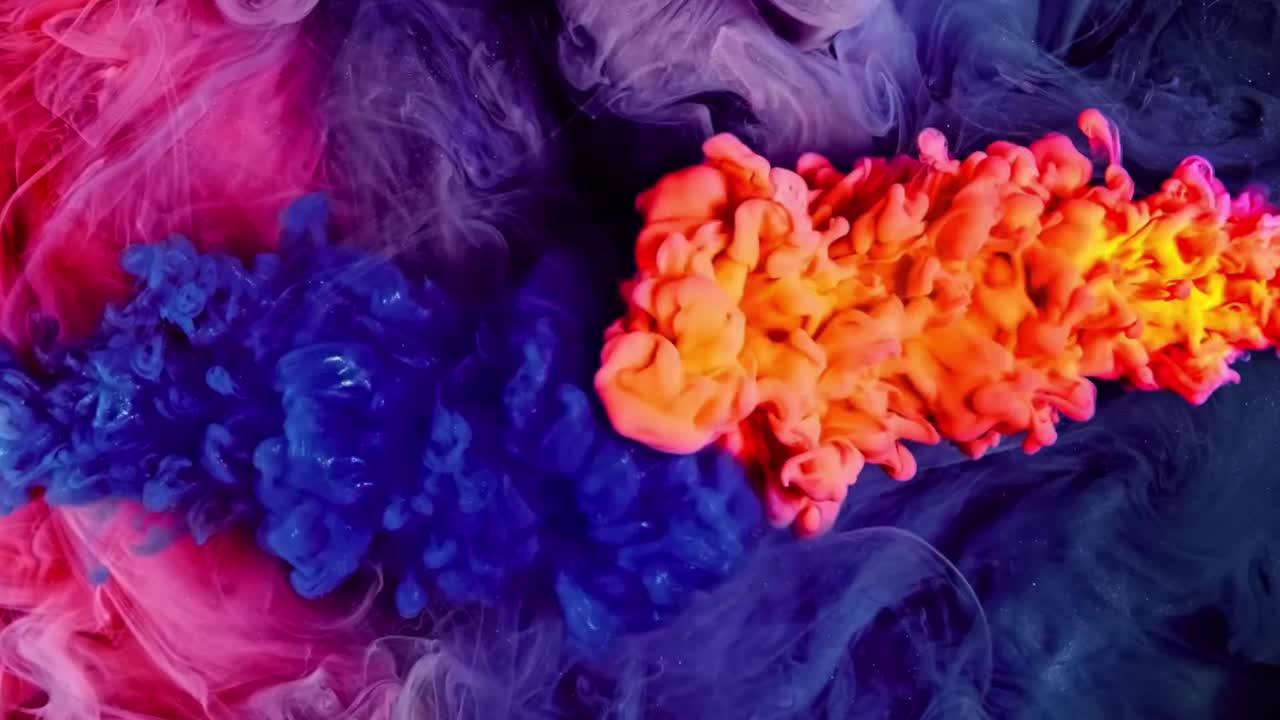 Gocce di inchiostro arancione, blu e rosa che si mescolano nell'acqua.
