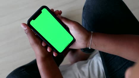 black woman holding smartphone green screen display