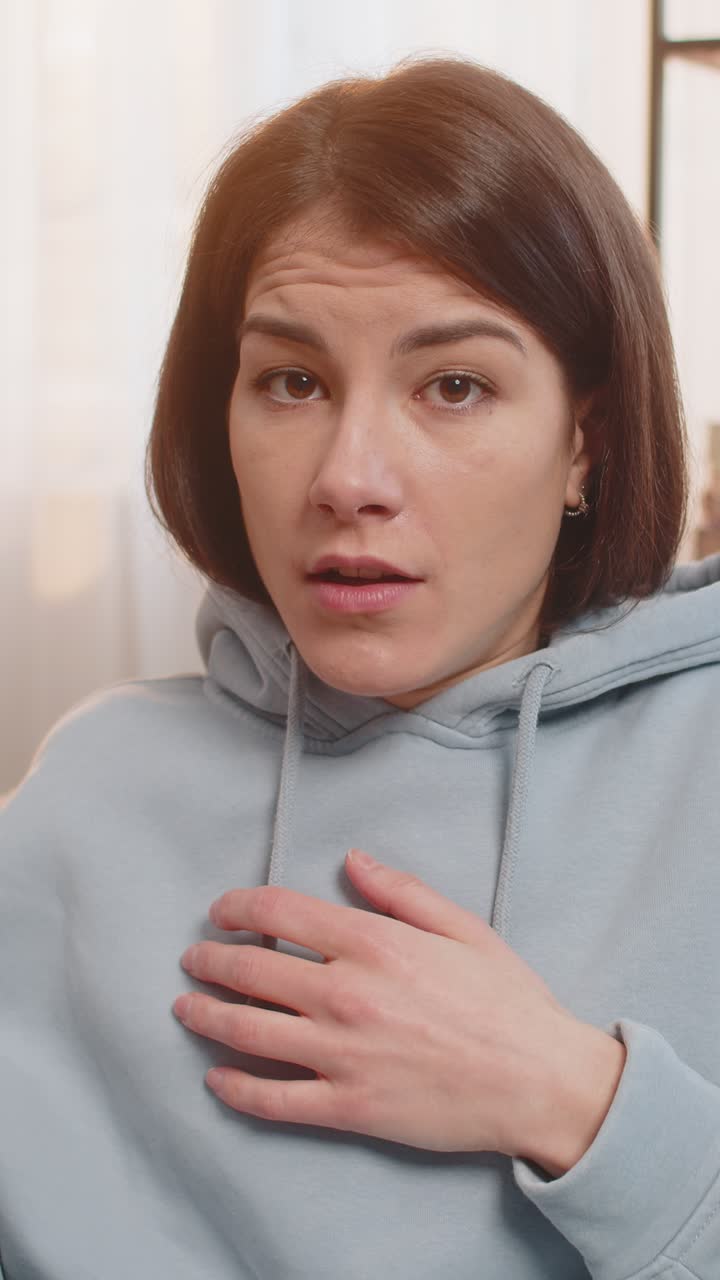 Confused caucasian woman on sofa raising eyebrows feeling embarrassed about ambiguous question