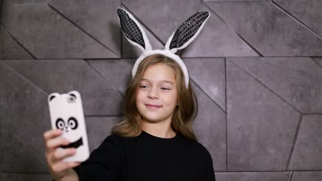 beautiful little brunette teen girl with bunny ears, they are taking selfie on smartphone