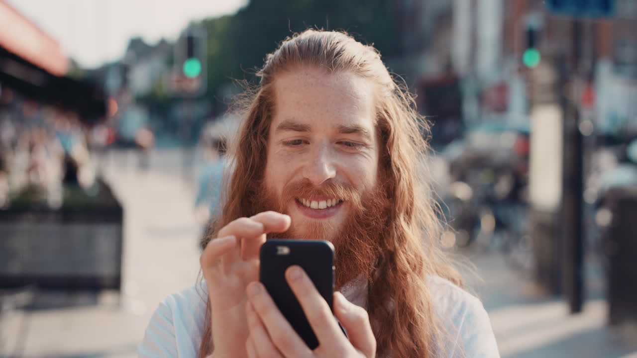 Ritratto in slow motion di un uomo hipster felice con la barba che usa lo smartphone