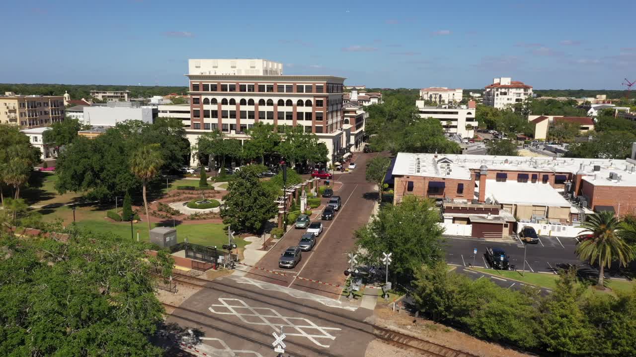 Low altitude aerial of Winter Park showing buildings and light midday traffic below as tram train crosses by