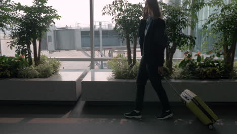 Woman-talking-on-mobile-while-walking-in-the-airport-terminal