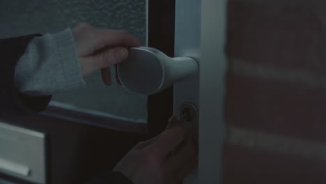 close up of girl putting key in lock of front door and walking inside