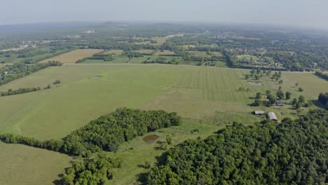 panorámica aérea de 4k alrededor de la granja del sur con campos verdes abiertos y un pequeño estanque