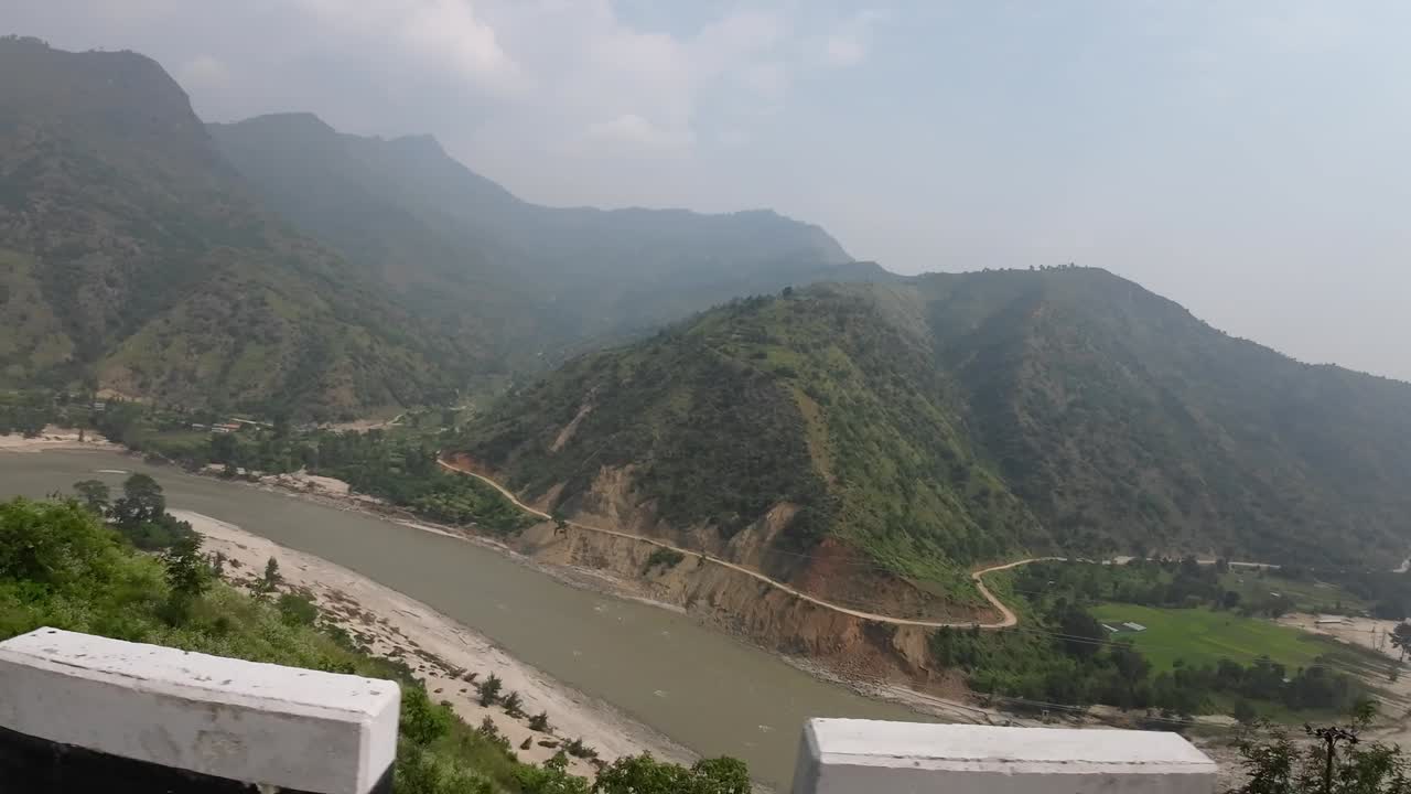 POV jeep ride through Nepal's rugged interior. Camera pan to the side down onto the deep valley and Sunkoshi River. Another jeep in front