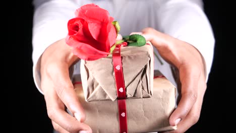 hands holding gifts with a red rose