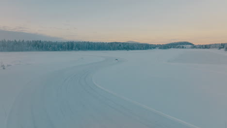 aerial view chasing norbotten driver drifting corners on frozen lapland ice lake at sunrise