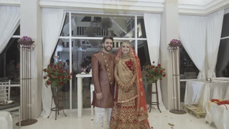 indian bride and groom on their wedding day taking photos inside the reception hall