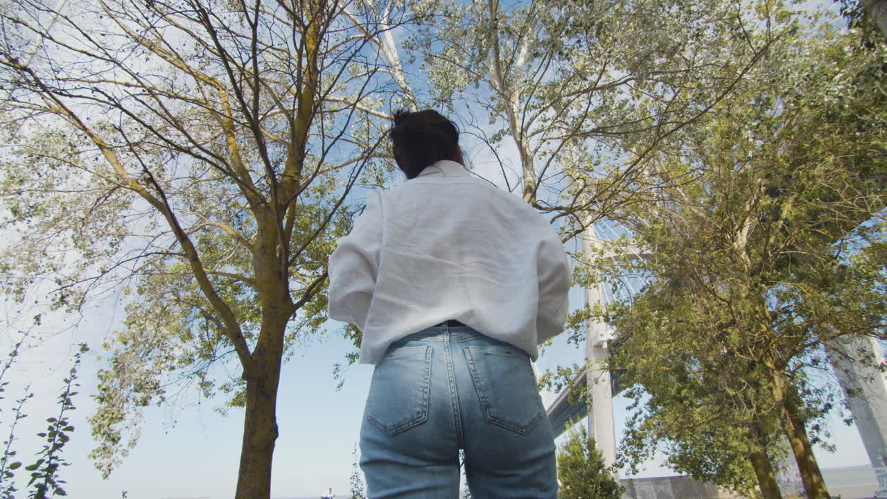 Young woman enjoys nature. Takes a photo of the trees
