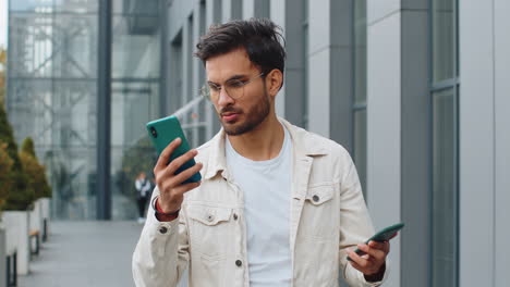 irritated stressed business man talking on two mobile phones having conversation conflict quarrel