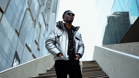 a man in a silver jacket and sunglasses standing on a set of stairs