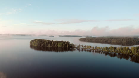 panning over a very calm and serene lake with several islands in the autumn