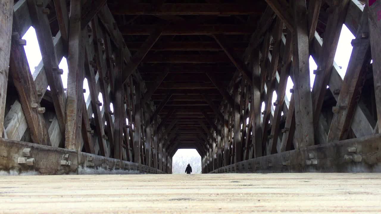 오래되고 나무로 덮힌 강 다리의 다른 쪽 끝에서 외로운 그림 출구 보도의 낮은 각도