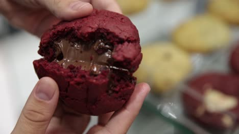 rompiendo una galleta de terciopelo rojo recién respaldada para mostrar el pegajoso chocolate derretido en el interior - primer plano