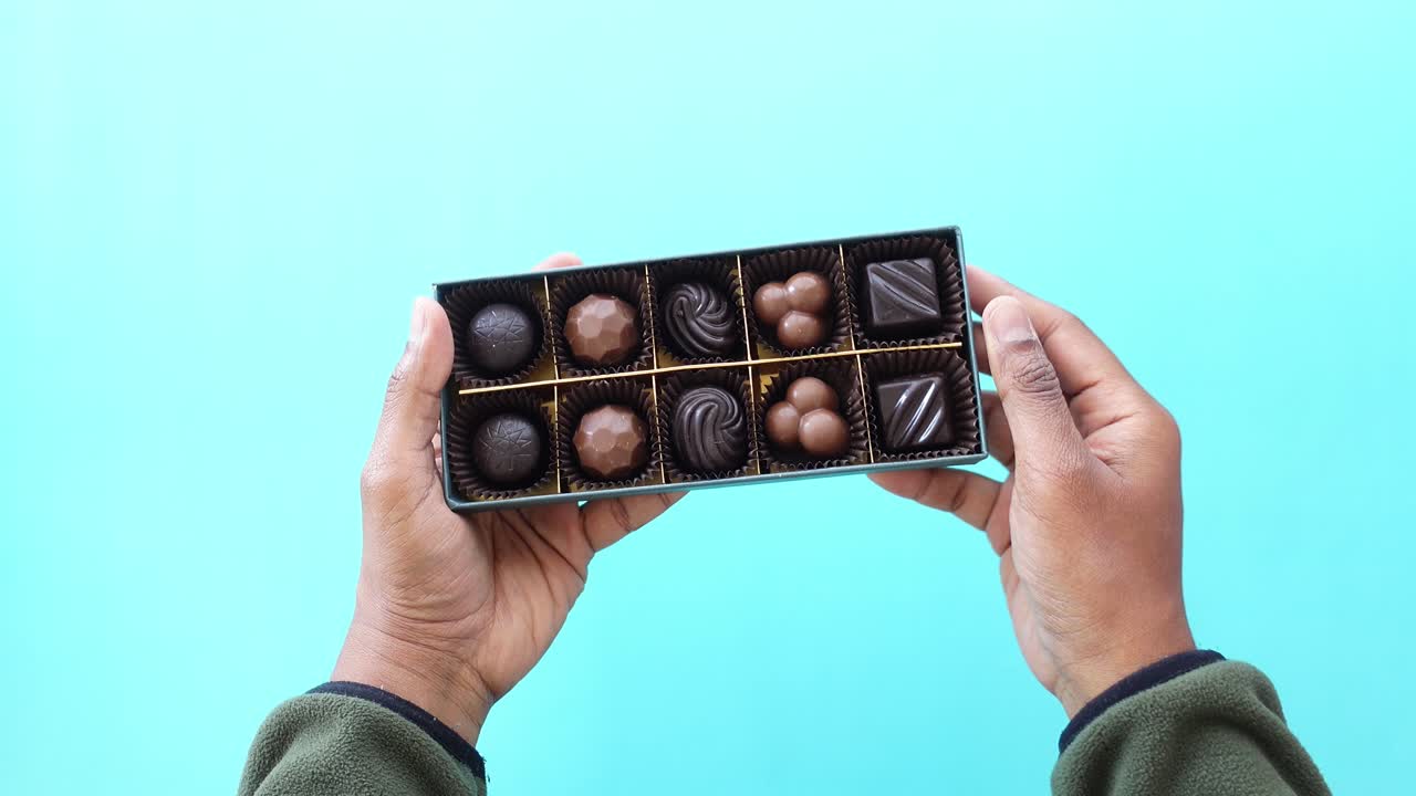 manos sosteniendo una caja de chocolates variados