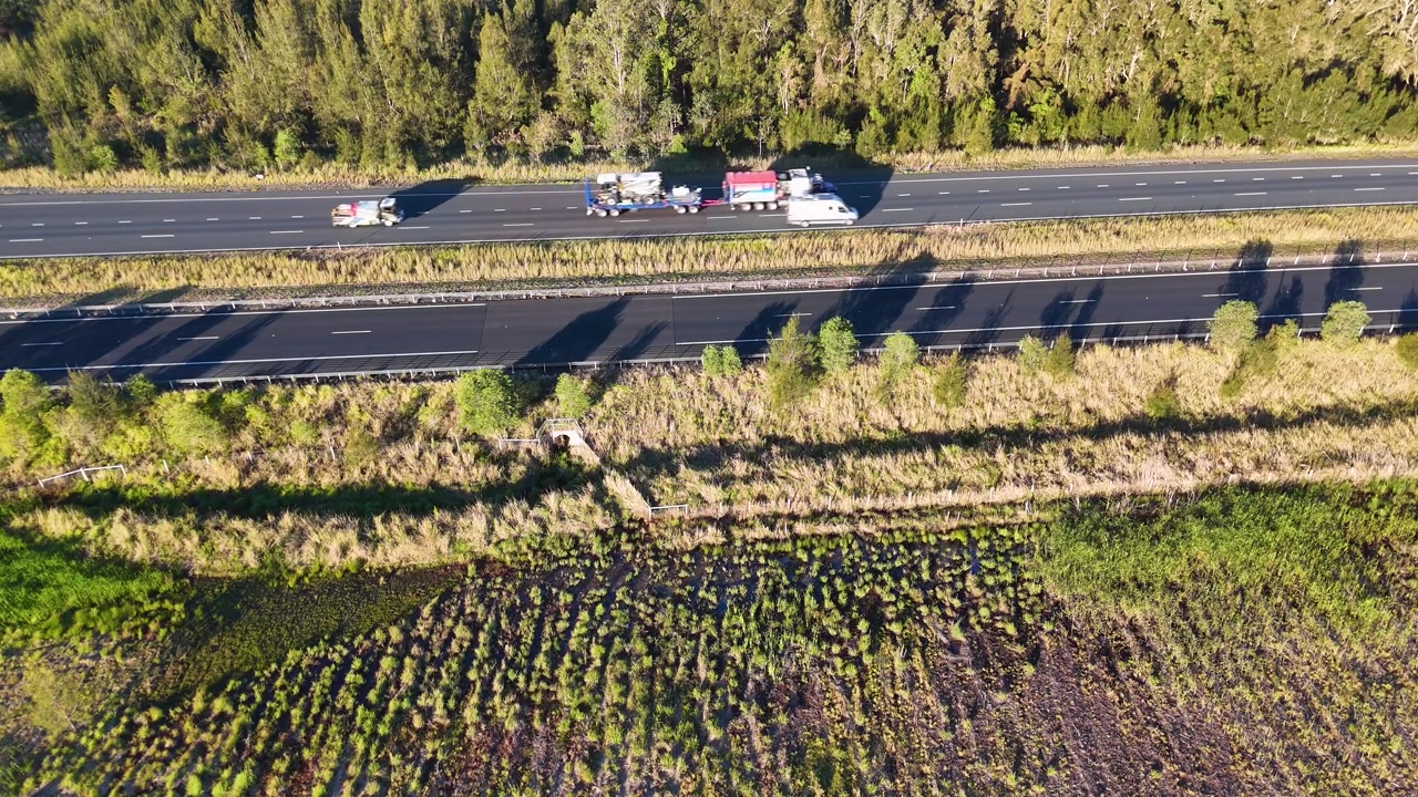 High-angle drone shot of a freight truck traveling along a rural highway in Australia.