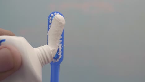 applying toothpaste to a toothbrush