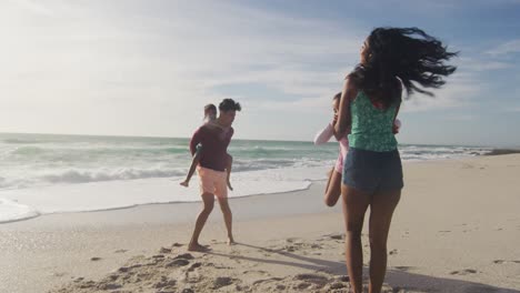 padres hispanos felices jugando con sus hijos en la playa bajo el sol
