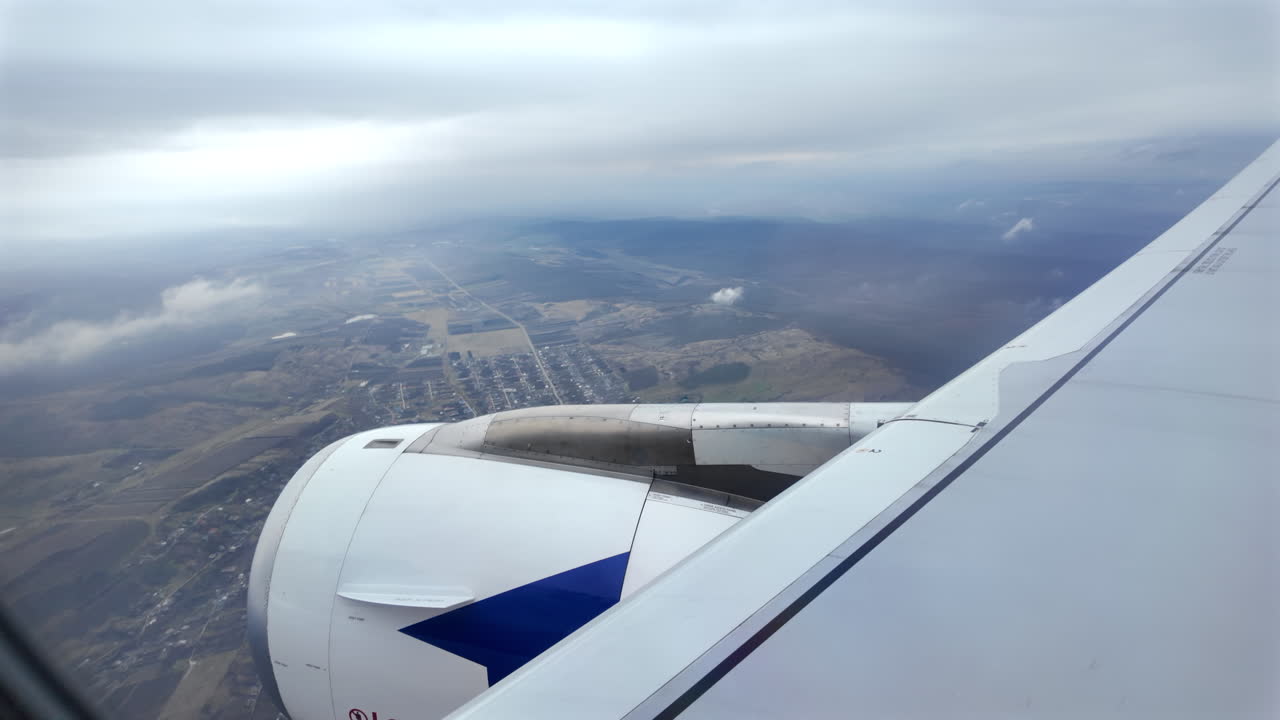 View from an airplane window of houses and fields while a plane is preparing to land