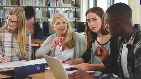 female teacher working with college students in library