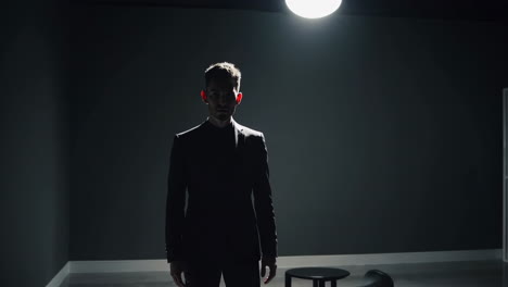 a man in a dark room under a single spotlight