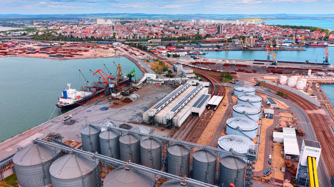 Draufsicht auf ein maritimes Getreideterminal und Lagertanks. Detaillierte Luftaufnahme einer industriellen Hafenanlage mit großen zylindrischen Stahlsilos und Bahnanlagen.
