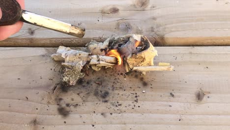 closeup point of view shot of setting paper on fire on wooden plank