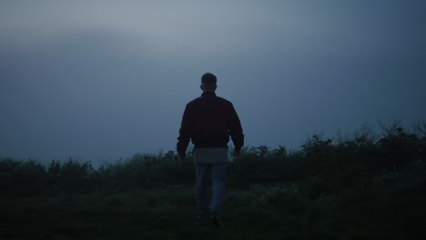 casual man walking in field. inspired guy felling freedom in foggy landscape