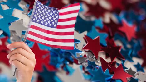 Animation-of-person-holding-american-flag-with-stars-in-background